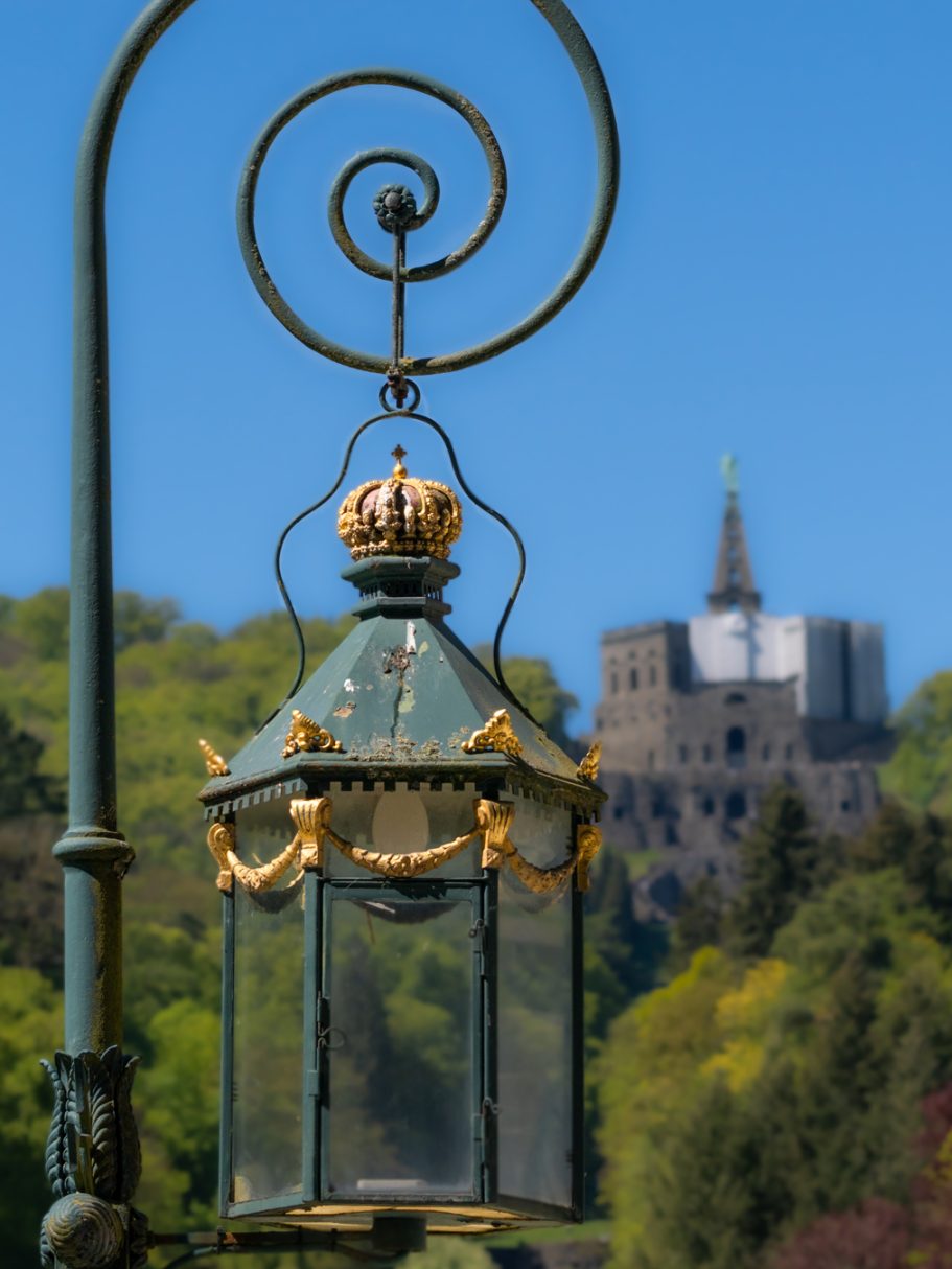 Laterne im Vordergrund mit einer königlichen Krone, Hintergrund zeigt eine Burg.