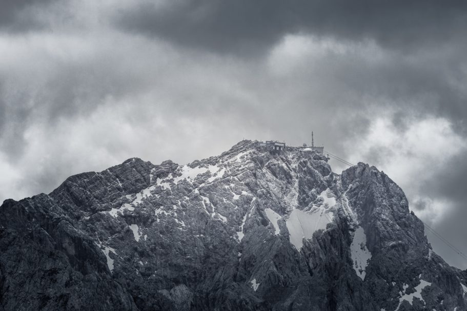 Schneebedeckte Bergspitze unter einem bewölkten, dramatischen Himmel.