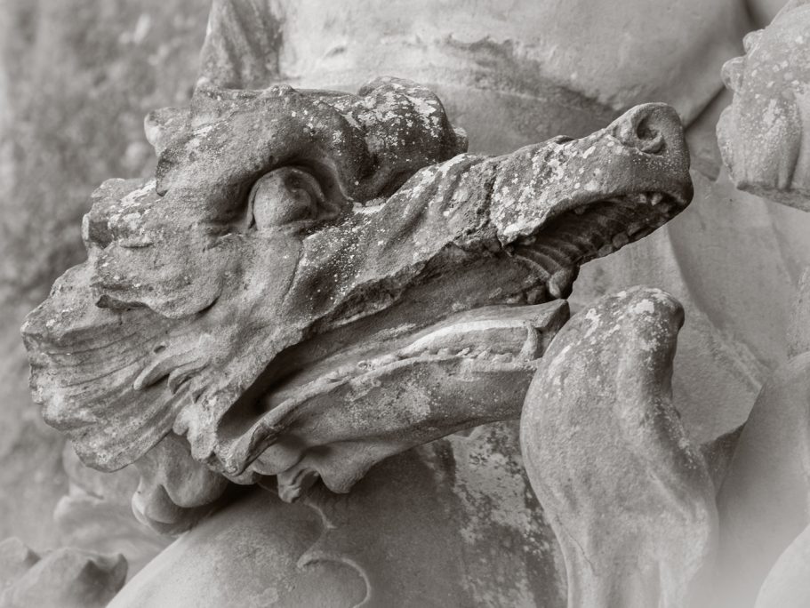 Detaillierte Skulptur eines Drachenkopfs in grauem Stein.