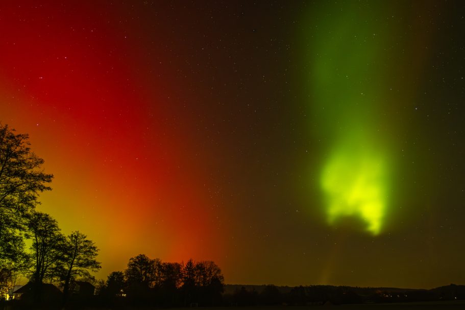 Bunt leuchtende Nordlichter in einem Nachthimmel mit grünen und roten Farbtönen.